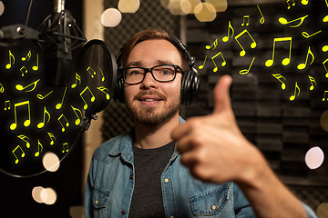 Image showing man with headphones singing at recording studio