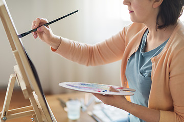 Image showing artist with palette and brush painting at studio