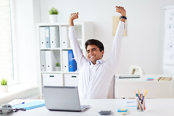 Image showing tired businessman with laptop stretching at office