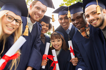 Image showing happy students in mortar boards with diplomas