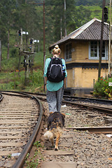 Image showing Female backpacker walking on railroad track followed by her dog.