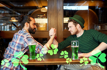 Image showing men drinking green beer and arm wrestling at pub