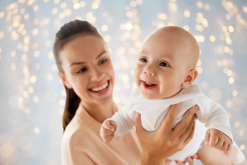 Image showing happy mother playing with little baby over lights