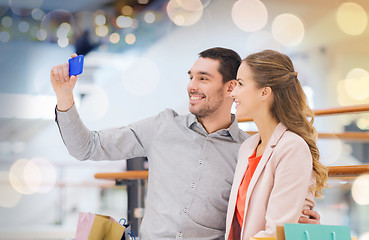 Image showing happy couple with smartphone taking selfie in mall