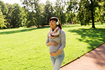 Image showing happy pregnant asian woman in headphones at park