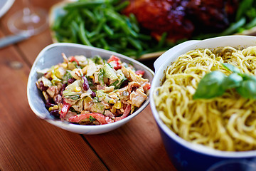 Image showing salad and pasta in bowls with other food on table