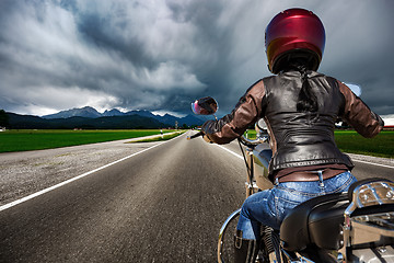 Image showing Biker girl on a motorcycle hurtling down the road in a lightning