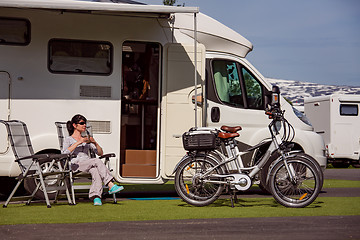 Image showing Woman is standing with a mug of coffee near the camper RV.