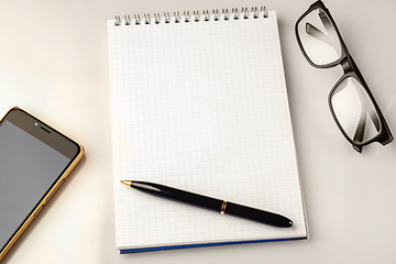 Image showing Work space accessories: pen, notebook, glasses and a modern smartphone