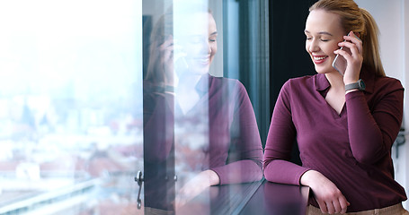 Image showing Elegant Woman Using Mobile Phone by window in office building