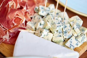 Image showing blue cheese and jamon or parma ham on wooden board