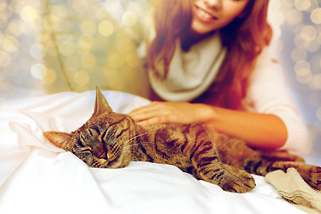 Image showing happy young woman with cat lying in bed at home