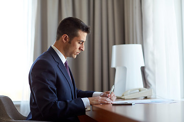 Image showing businessman with papers working at hotel room