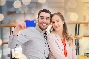 Image showing happy couple with smartphone taking selfie in mall