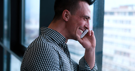 Image showing Business Man Talking On Cell Phone, Looking Out Office Window