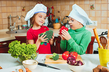 Image showing happy family funny kids are preparing the a fresh vegetable salad in the kitchen