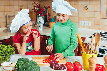 Image showing happy family funny kids are preparing the a fresh vegetable salad in the kitchen