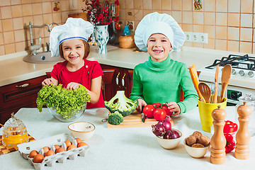 Image showing happy family funny kids are preparing the a fresh vegetable salad in the kitchen