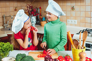 Image showing happy family funny kids are preparing the a fresh vegetable salad in the kitchen