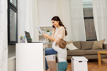 Image showing happy mother with baby and papers working at home