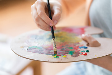 Image showing artist with palette and brush painting at studio