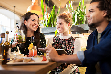 Image showing happy friends eating and drinking at bar or cafe