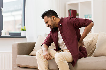 Image showing unhappy man suffering from backache at home