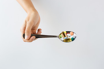 Image showing close up of female hand holding spoon with pills