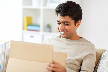 Image showing happy man opening parcel box at home