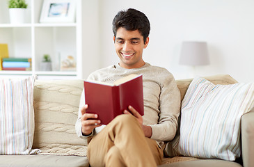 Image showing man sitting on sofa and reading book at home