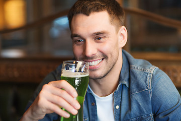 Image showing close up of man drinking green beer at bar or pub