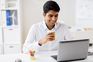 Image showing businessman with laptop drinking coffee at office