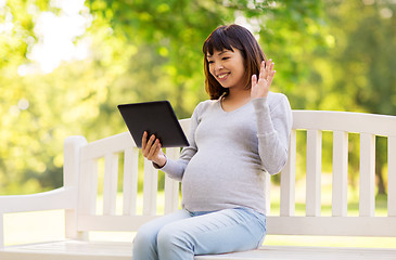 Image showing happy pregnant asian woman with tablet pc at park