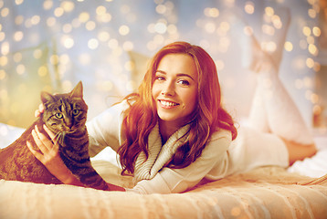 Image showing happy young woman with cat lying in bed at home