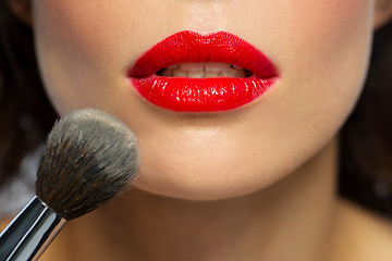 Image showing face of woman with red lipstick applying powder