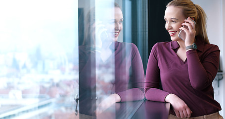 Image showing Elegant Woman Using Mobile Phone by window in office building