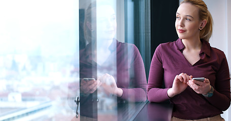 Image showing Elegant Woman Using Mobile Phone by window in office building