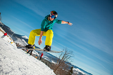 Image showing Bukovel, Ukraine - December 22, 2016: Man boarder jumping on his snowboard against the backdrop of mountains, hills and forests in the distance. Bukovel, Carpathian mountains