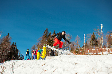 Image showing Bukovel, Ukraine - December 22, 2016: Man boarder jumping on his snowboard against the backdrop of mountains, hills and forests in the distance. Bukovel, Carpathian mountains