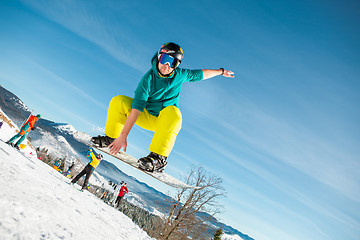 Image showing Bukovel, Ukraine - December 22, 2016: Man boarder jumping on his snowboard against the backdrop of mountains, hills and forests in the distance. Bukovel, Carpathian mountains