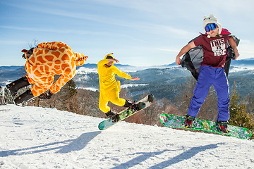 Image showing Bukovel, Ukraine - December 22, 2016: Men boarders jumping on his snowboard against the backdrop of mountains, hills and forests in the distance. Bukovel, Carpathian mountains