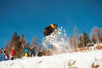 Image showing Bukovel, Ukraine - December 22, 2016: Man boarder jumping on his snowboard against the backdrop of mountains, hills and forests in the distance. Bukovel, Carpathian mountains