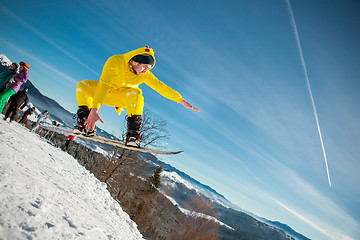 Image showing Bukovel, Ukraine - December 22, 2016: Man boarder jumping on his snowboard against the backdrop of mountains, hills and forests in the distance. Bukovel, Carpathian mountains