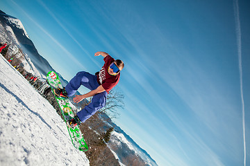 Image showing Bukovel, Ukraine - December 22, 2016: Man boarder jumping on his snowboard against the backdrop of mountains, hills and forests in the distance. Bukovel, Carpathian mountains