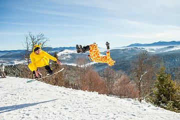 Image showing Bukovel, Ukraine - December 22, 2016: Men boarders jumping on his snowboard against the backdrop of mountains, hills and forests in the distance. Bukovel, Carpathian mountains