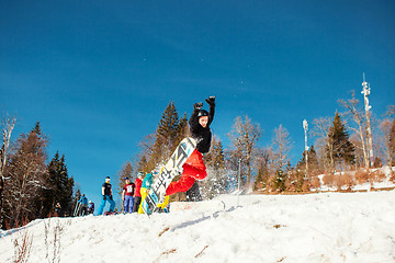 Image showing Bukovel, Ukraine - December 22, 2016: Man boarder jumping on his snowboard against the backdrop of mountains, hills and forests in the distance. Bukovel, Carpathian mountains