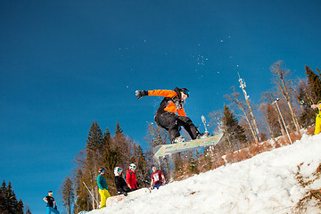 Image showing Bukovel, Ukraine - December 22, 2016: Man boarder jumping on his snowboard against the backdrop of mountains, hills and forests in the distance. Bukovel, Carpathian mountains