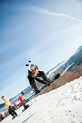 Image showing Bukovel, Ukraine - December 22, 2016: Man boarder jumping on his snowboard against the backdrop of mountains, hills and forests in the distance. Bukovel, Carpathian mountains