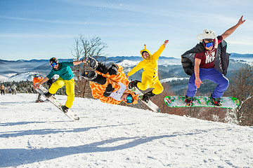 Image showing Bukovel, Ukraine - December 22, 2016: Men boarders jumping on his snowboard against the backdrop of mountains, hills and forests in the distance. Bukovel, Carpathian mountains