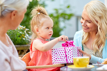 Image showing happy mother giving present to daughter at cafe